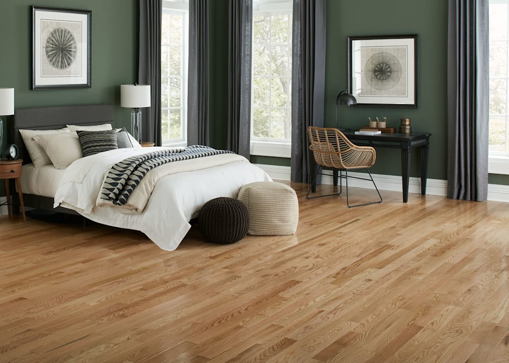 3/4 in x 3.25 in Natural Oak Solid Hardwood Flooring in bedroom with dark green walls plus dark gray bed and off white bedding and black wood desk with rattan desk chair