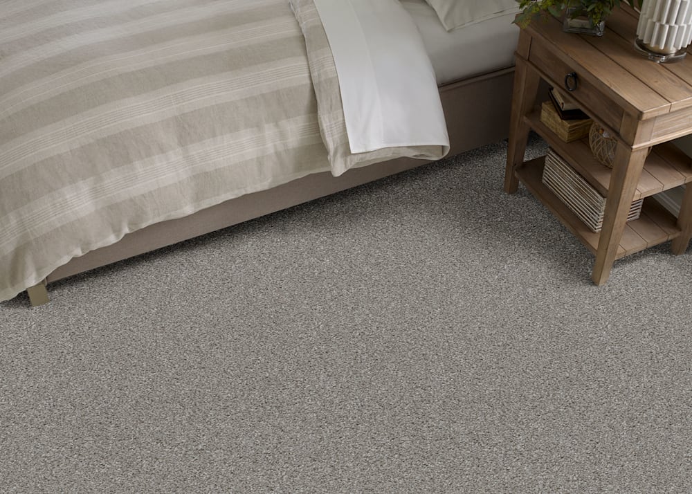 Huntington Beach Carpet in Foilage in bedroom with beige stripped bedding and medium wood tone side table