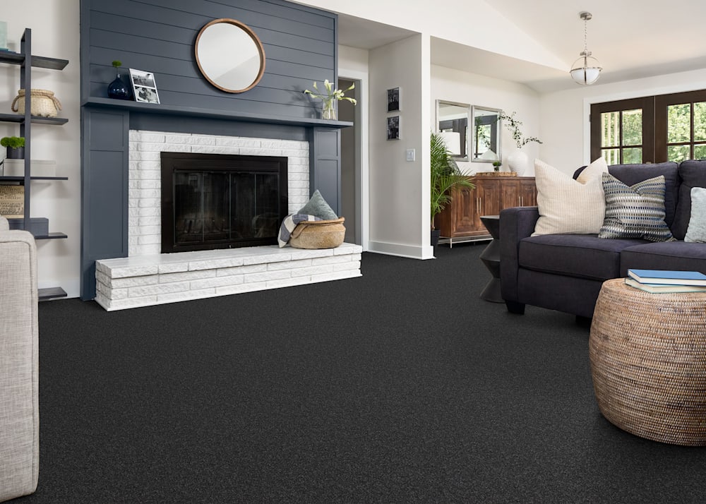 Croftstown Way Carpet in Obsidian in living room with dark gray shiplap surrounding fireplace and dark gray upholstered sofa