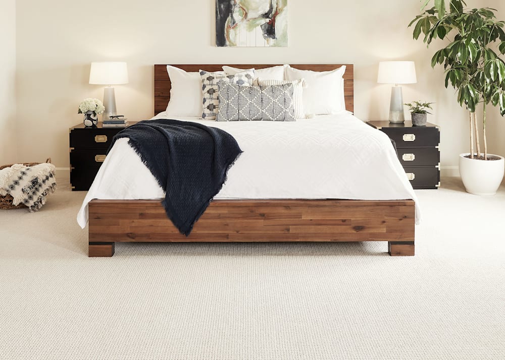 Baffin Bay Carpet in Farro in bedroom with medium wood tone low bed with white bedding and black and gold side tables