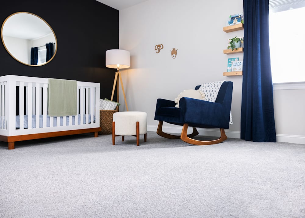 San Lucinda Carpet in Cozy in nursery with dark blue upholstered rocking chair and white crib with green blanket