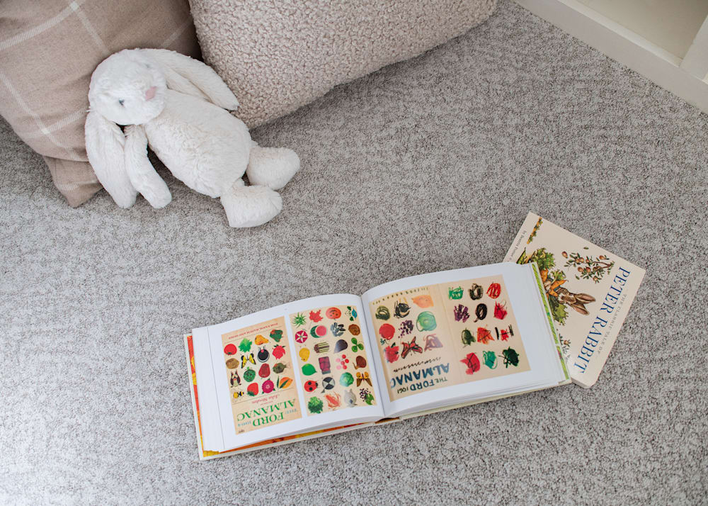 Jolly Harbour Carpet in Marble in playroom with beige accent pillows and white stuffed bunny and colorful animal book