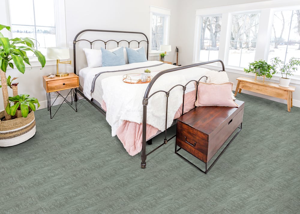 Bronx Village Carpet in Seascape in bedroom with wrought iron bed and white and blush bedding plus light wood bench and side table